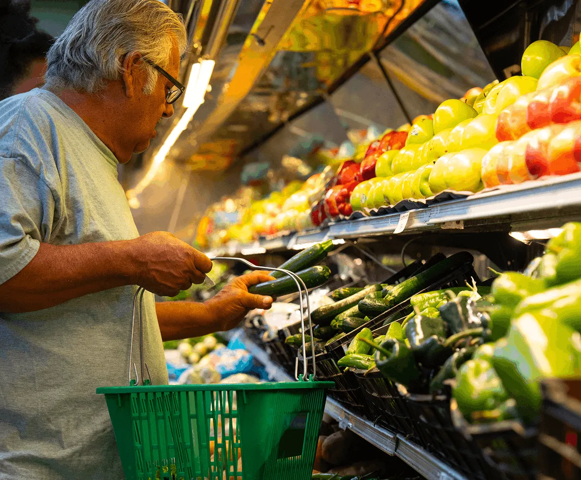 Customer selecting fresh vegetables in the produce section at Juniors Market