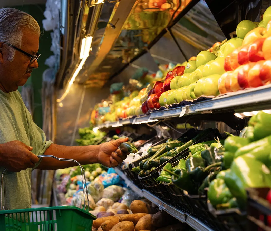 Customer selecting fresh vegetables and produce inside Juniors Market grocery store