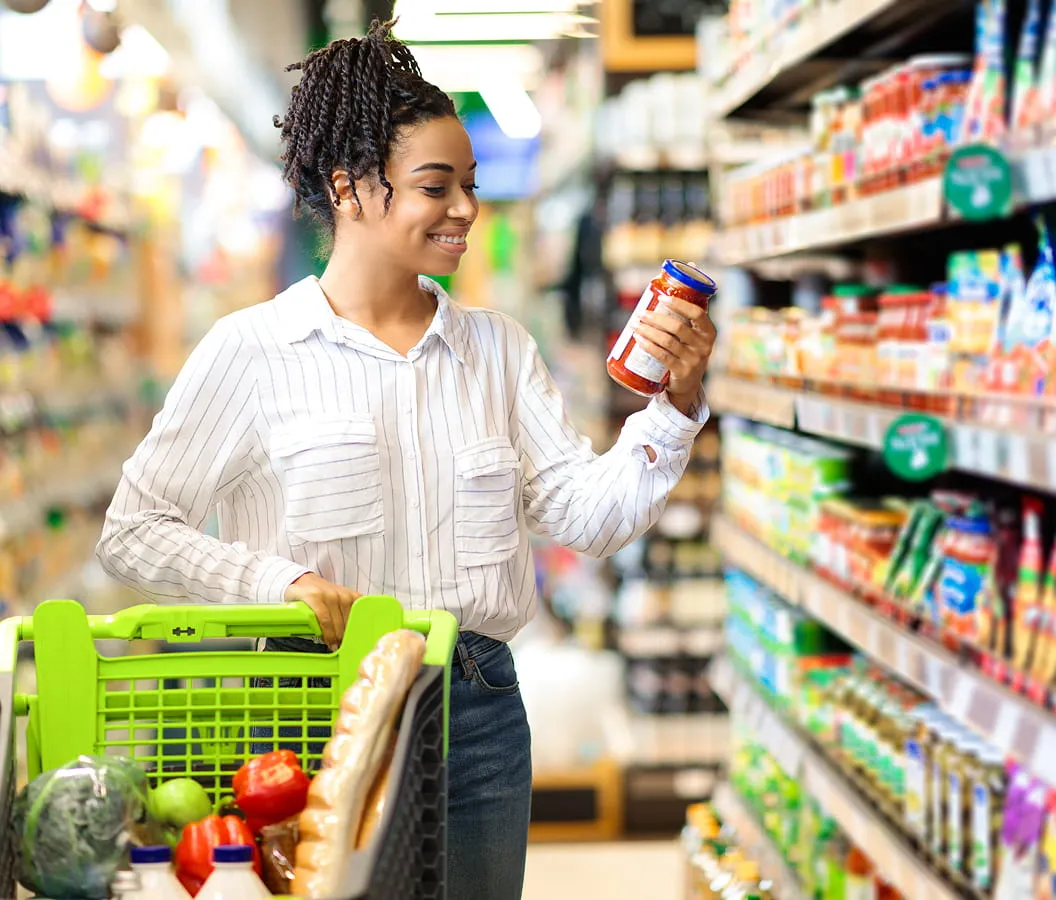 Customer shopping in grocery aisle and checking product label at Juniors Market store