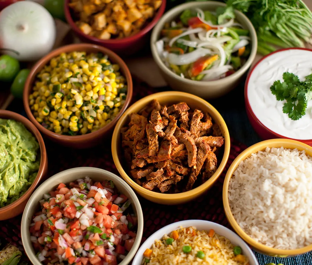 Fresh ingredients including rice, beans, guacamole, salsa, and seasoned meat at Juniors Market kitchen section